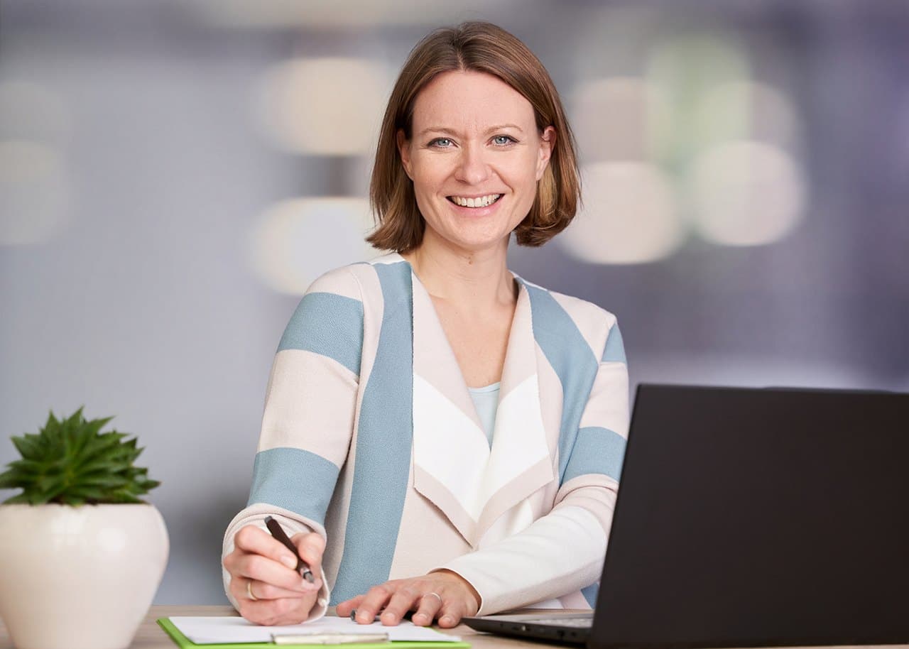 Jennifer Rohdenburg sitzt mit Stift und Laptop am Schreibtisch