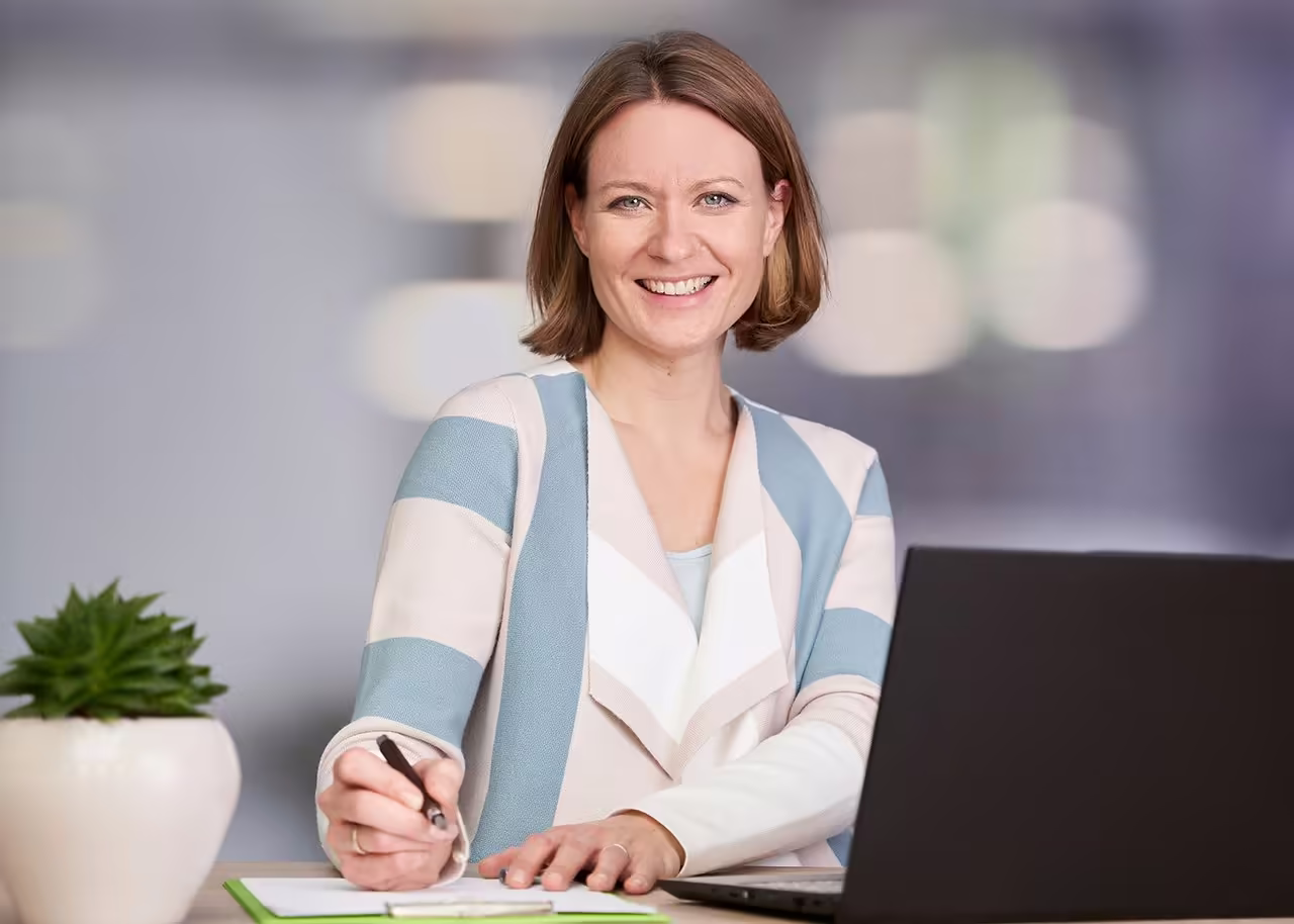 Jennifer Rohdenburg sitzt mit Stift und Laptop am Schreibtisch